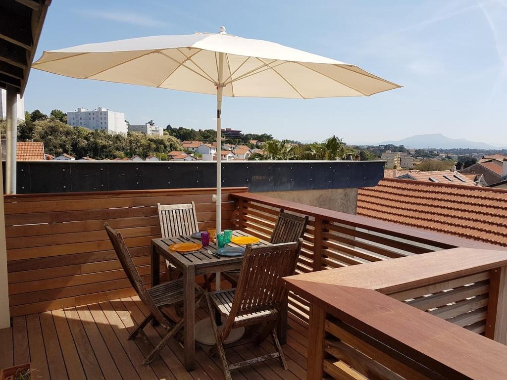 une table et des chaises avec un parasol sur une terrasse dans l'établissement Biarritz - Beaurivage - Proche cote des Basques, à Biarritz