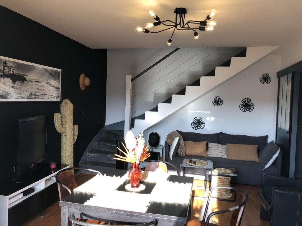 - un salon avec une table et un canapé avec un escalier dans l'établissement Biarritz - Petricot - Balcon - Calme, à Biarritz
