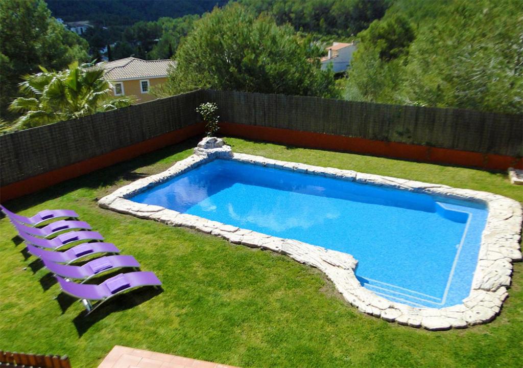 een zwembad met twee paarse ligstoelen in een tuin bij Villa Sitges El Olivo High Comodity AC Pool Heated Optional Real Garden Pool XXL in Olivella