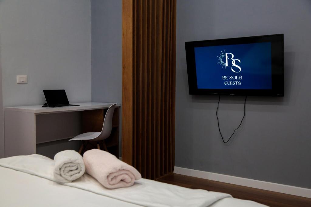 um quarto com uma cama e uma televisão na parede em Be Solei Studio Apartments Sol 1 em Tirana