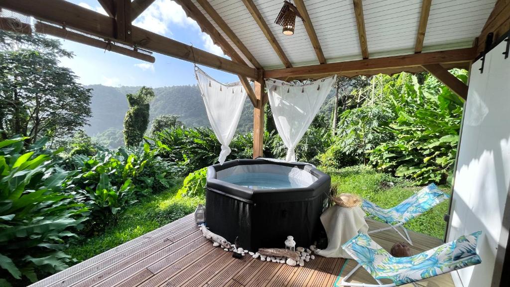 a porch with a hot tub and chairs on a deck at Chalet de Dolé in Gourbeyre