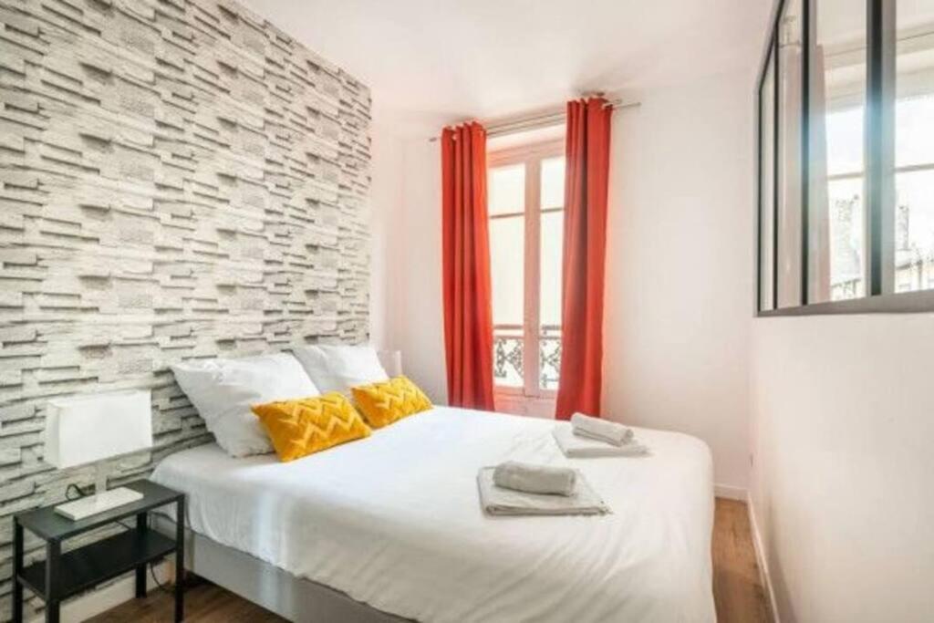 - une chambre avec un lit blanc et un mur en briques dans l'établissement Nets Inn Apartments - La Villette, à Paris