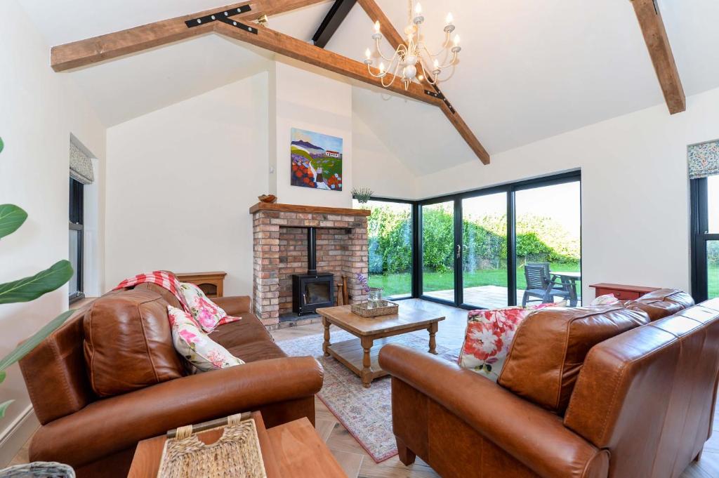 a living room with leather furniture and a fireplace at Bramble Cottage, hidden gem in Comber near Belfast in Ballygowan