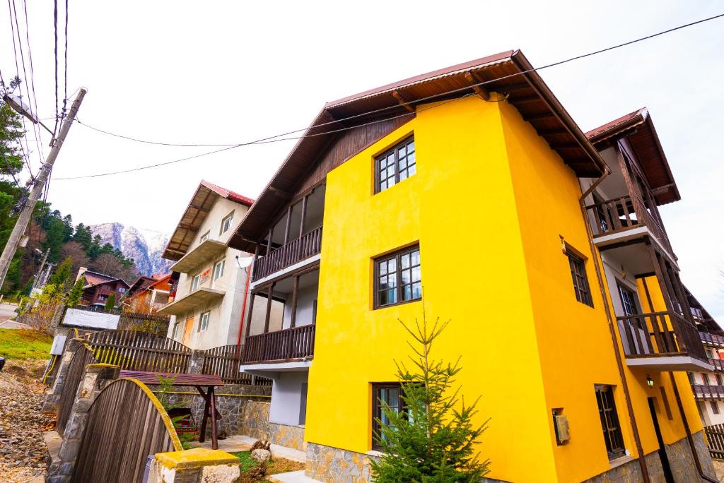 a yellow building with a brown roof at Casa Valentino in Buşteni