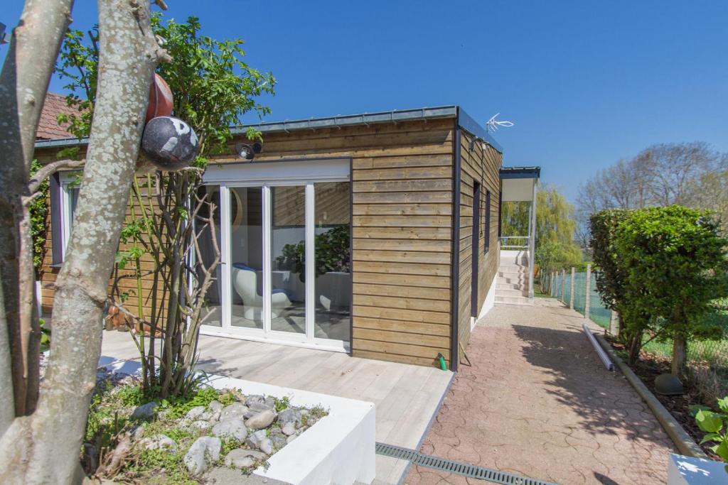 ein kleines Holzhaus mit einem Baum auf einem Gehweg in der Unterkunft Abri Cotier in Hautot-sur-Mer