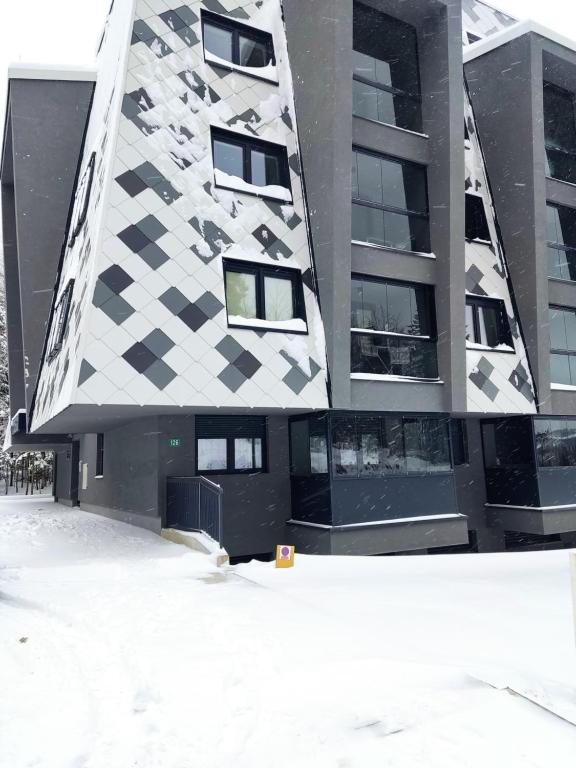 un edificio con una fachada a cuadros en la nieve en Apartman Virgin Forest - FREE Garage Bjelašnica en Bjelašnica