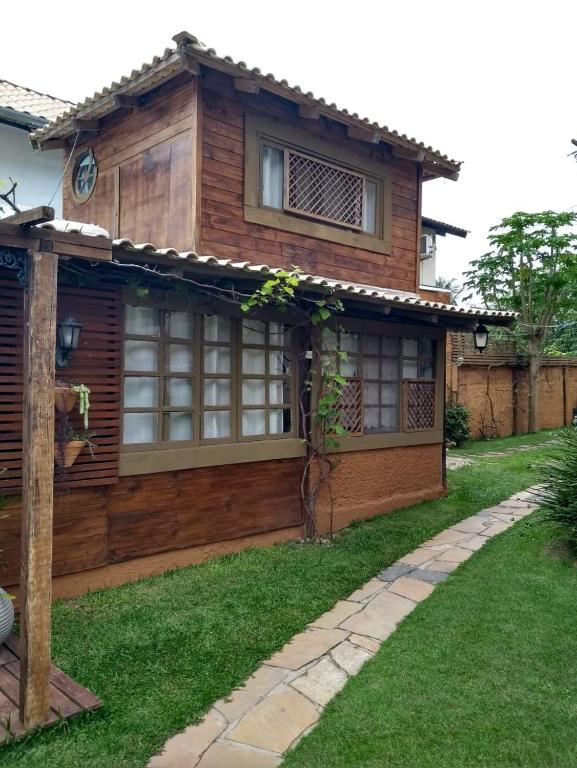 una casa de madera con césped delante en Casa Rústica Lisboa 100m da praia en Balneário Camboriú
