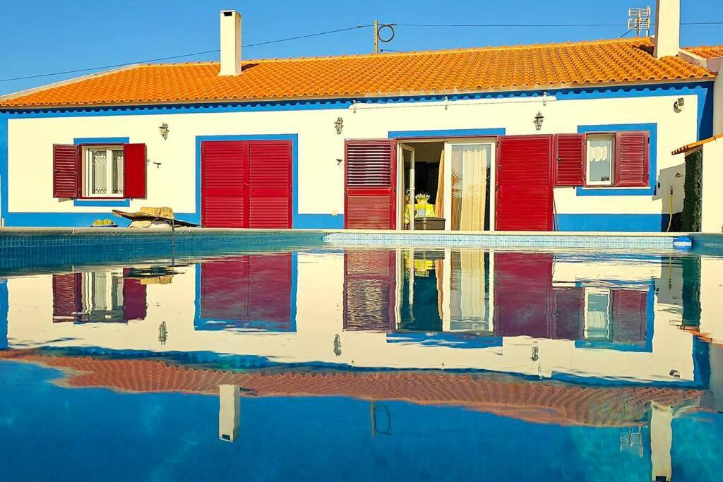 a house with red doors and a reflection in the water at Ferroa Guest House in Cano