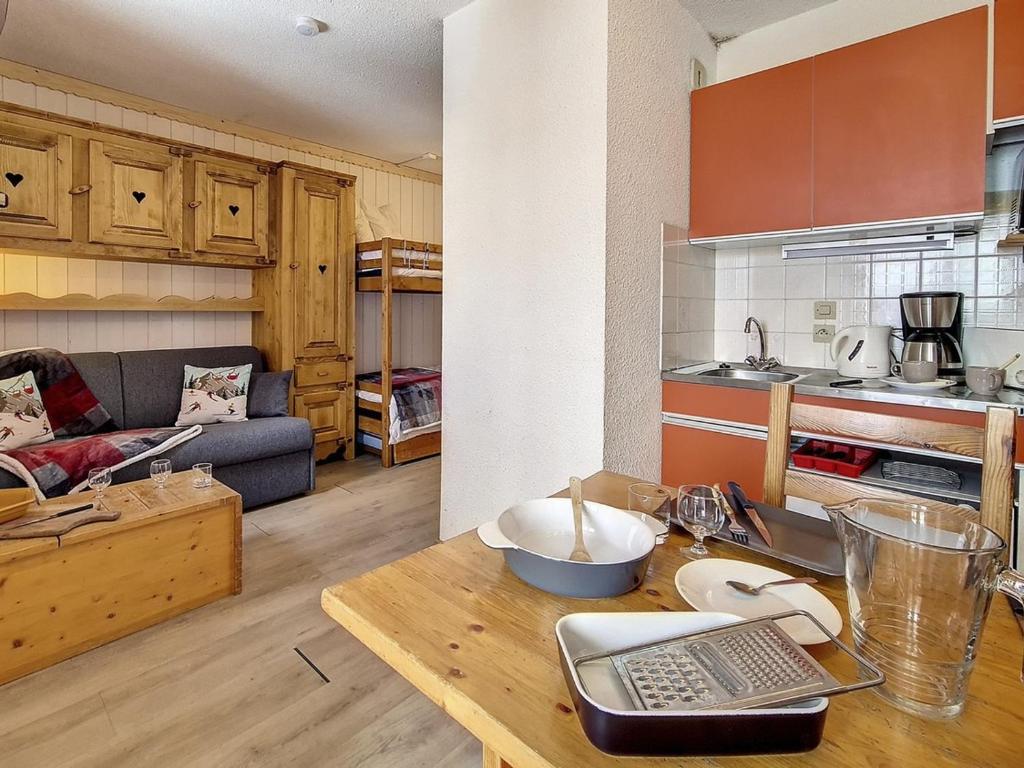 d'une cuisine et d'un salon avec une table et un canapé-lit. dans l'établissement Studio classique aux Menuires, balcon, animaux admis - FR-1-344-1038, aux Menuires