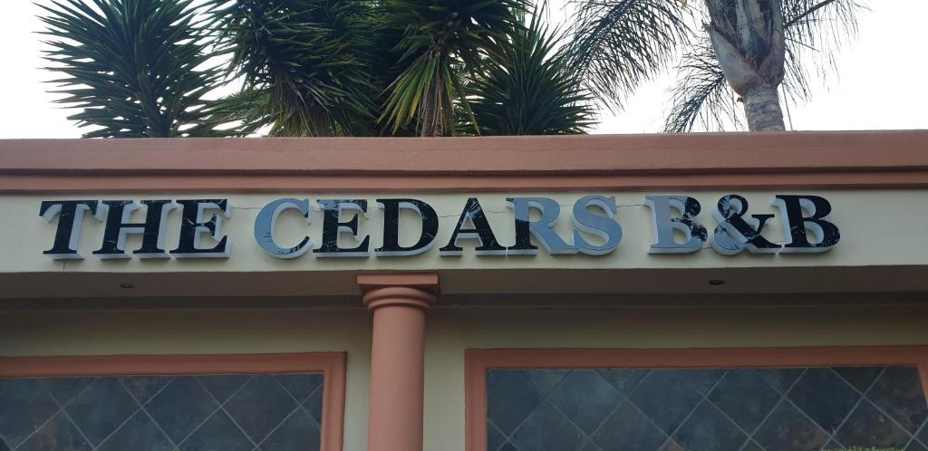 a sign on top of a building with palm trees at The Cedars Bed and Breakfast in Centurion