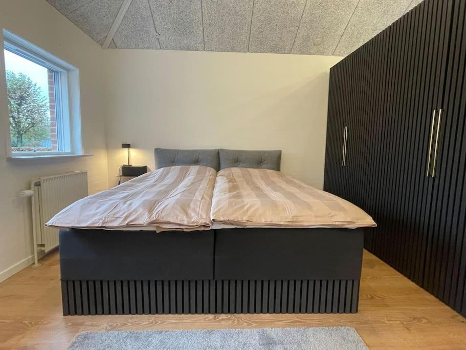 ein Bett in einem Schlafzimmer mit einem schwarzen Schrank in der Unterkunft Hyggelig nyrenoveret lejlighed til 4 Personer in Agerbæk