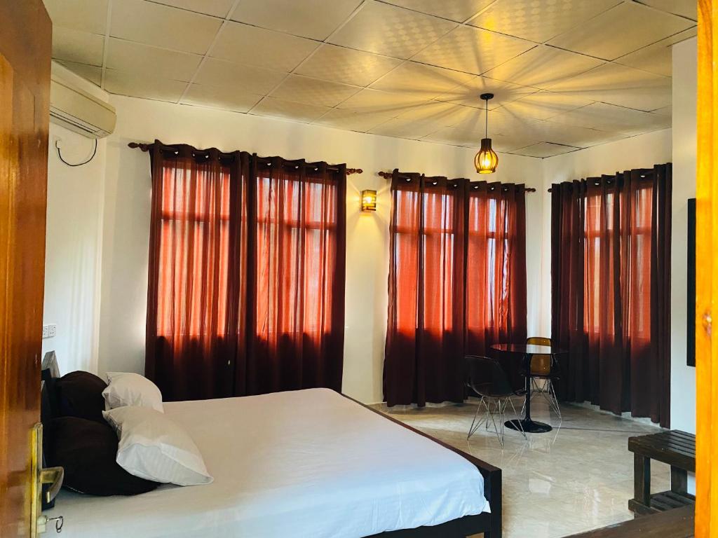 1 dormitorio con cortinas rojas y 1 cama grande en Aramba Resort, en Dondra West
