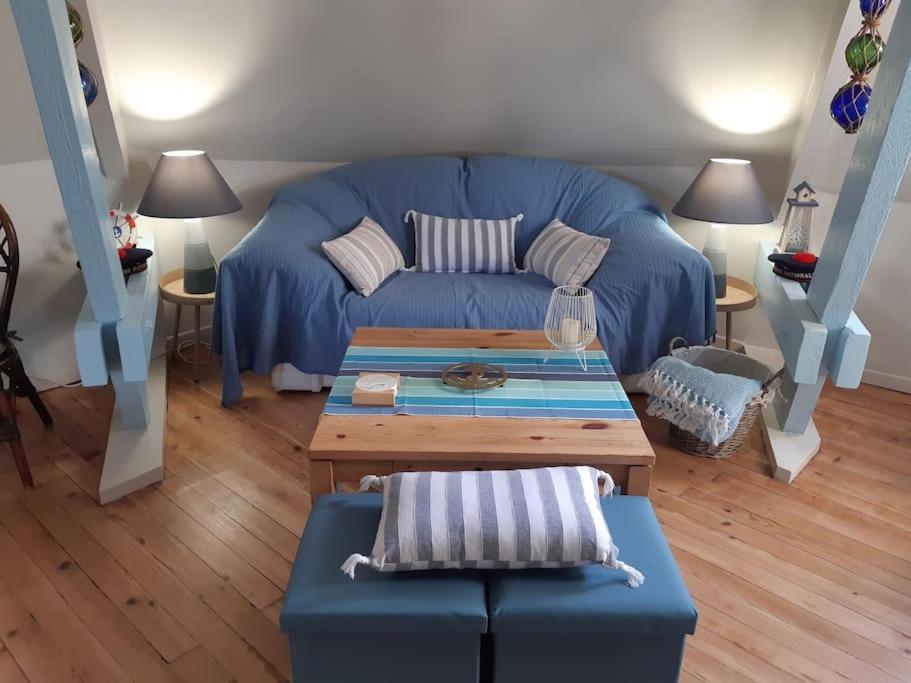 ein Wohnzimmer mit einem blauen Sofa und einem Tisch in der Unterkunft "Le Petit Marin", 2 ch, parking privé, 5 mn plage in Le Portel