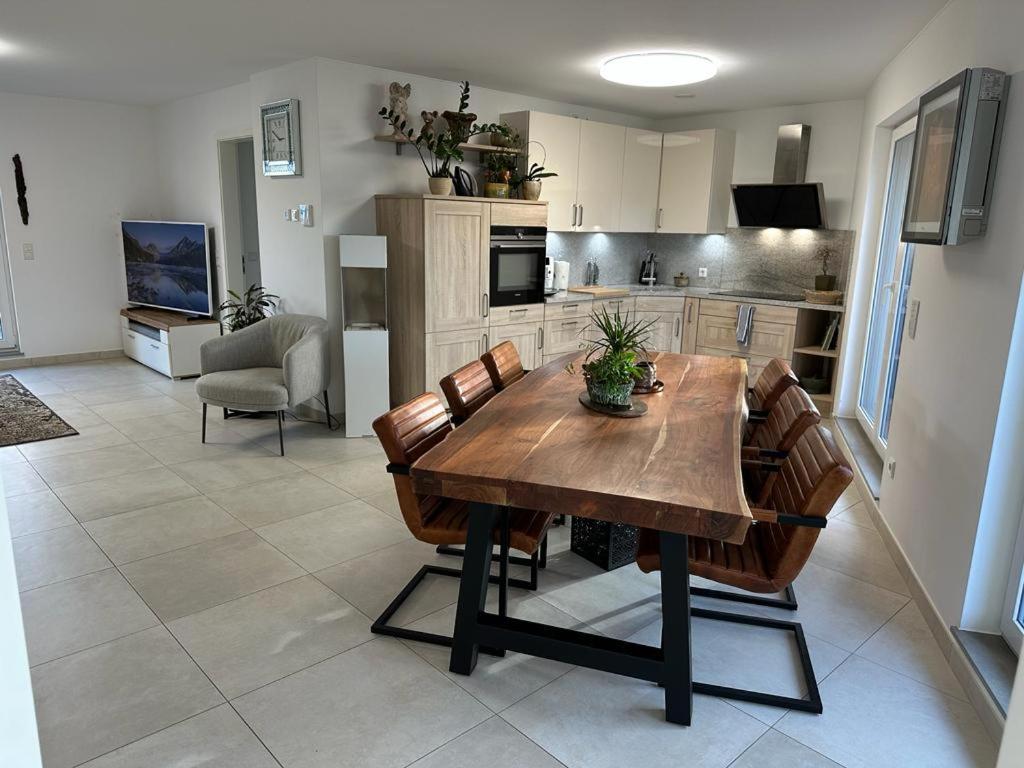 a kitchen and dining room with a wooden table and chairs at Appartement de luxe avec parking in Kayl