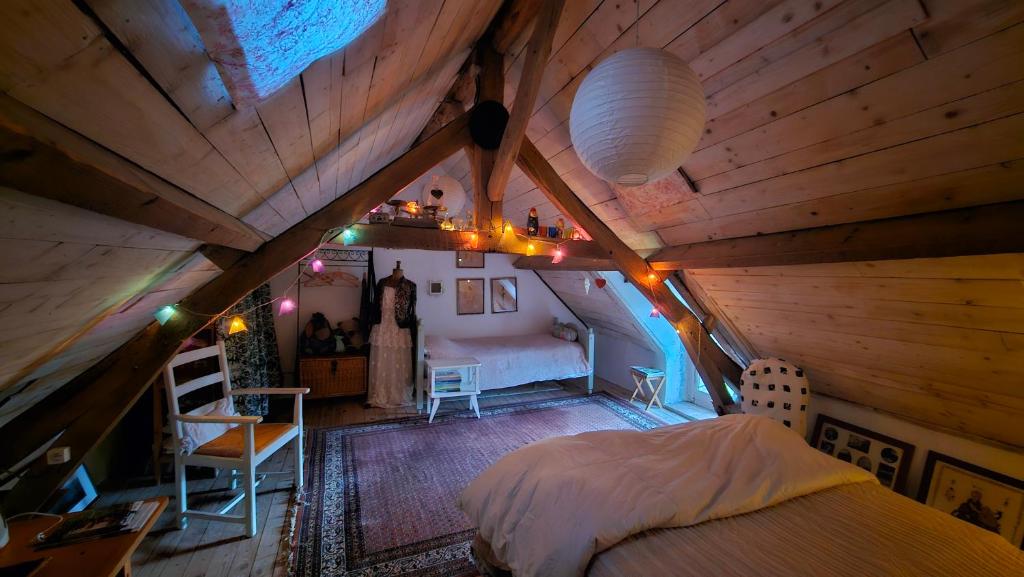 a bedroom with a bed in a wooden attic at Longère Typique — Charmante chambre d'Hôte 