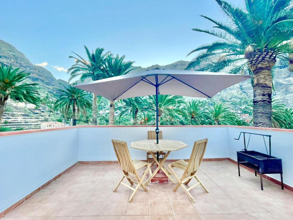 una mesa y sillas con una sombrilla en el balcón en La Casa de Aramita, en Valle Gran Rey