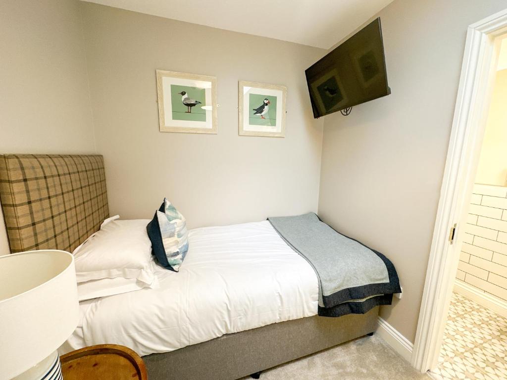 a small bedroom with a bed and two pictures on the wall at Beach House Hotel in Seahouses