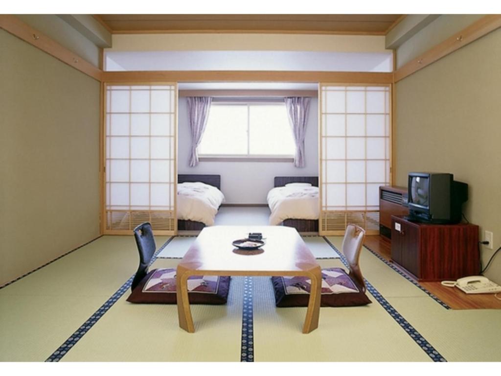 志賀高原にあるShiga Palace Hotel - Vacation STAY 22531vのテーブル、ベッド2台、窓が備わる客室です。