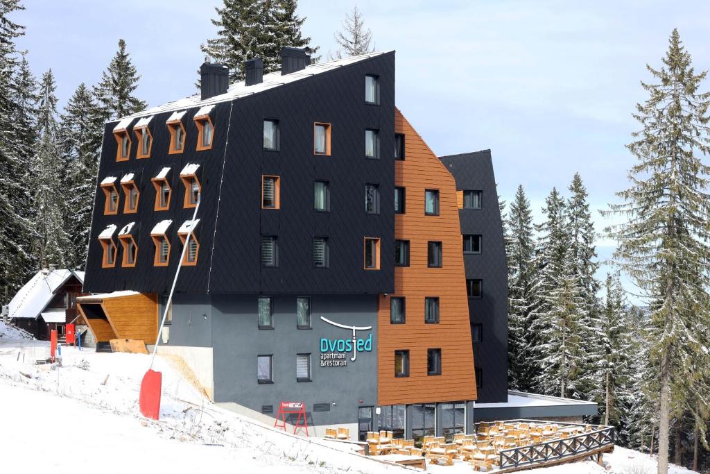 亚霍里纳Jahorina Dvosjed Apartman 6的一座在滑雪场上设有黑色屋顶的大型建筑