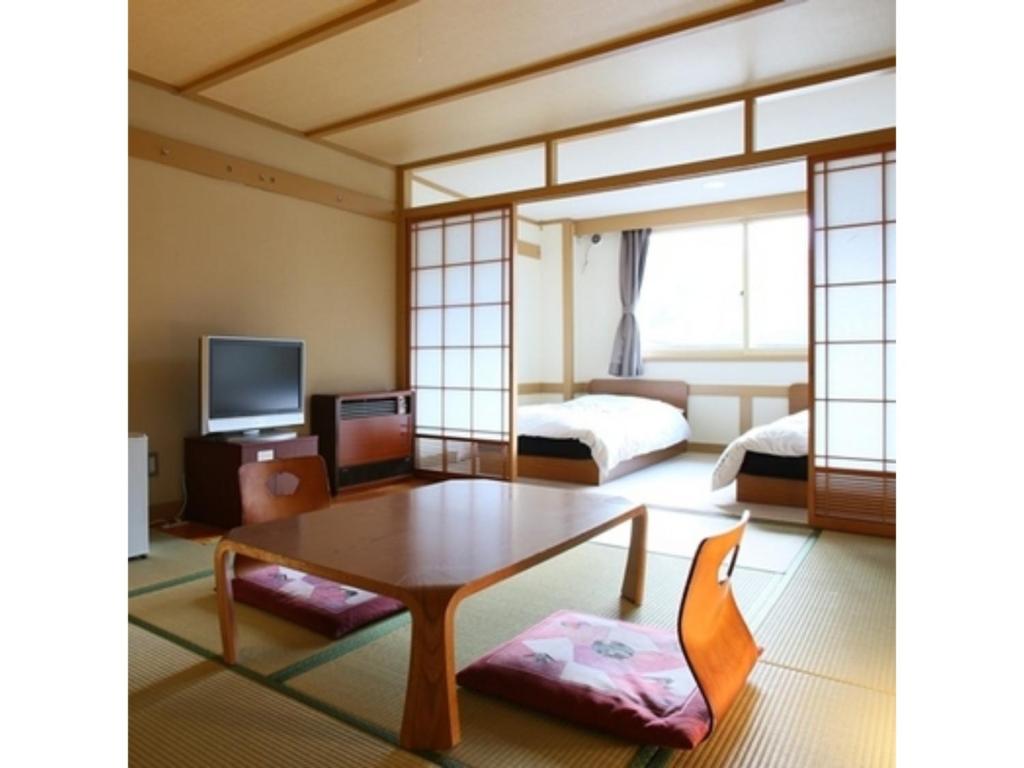 a living room with a table and a bed and a tv at Shiga Palace Hotel - Vacation STAY 22530v in Shiga Kogen