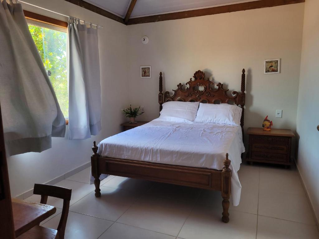a bedroom with a bed with white sheets and a window at Casa Corumbau temporada Recanto Ipê-Amarelo a 400m da praia in Corumbau