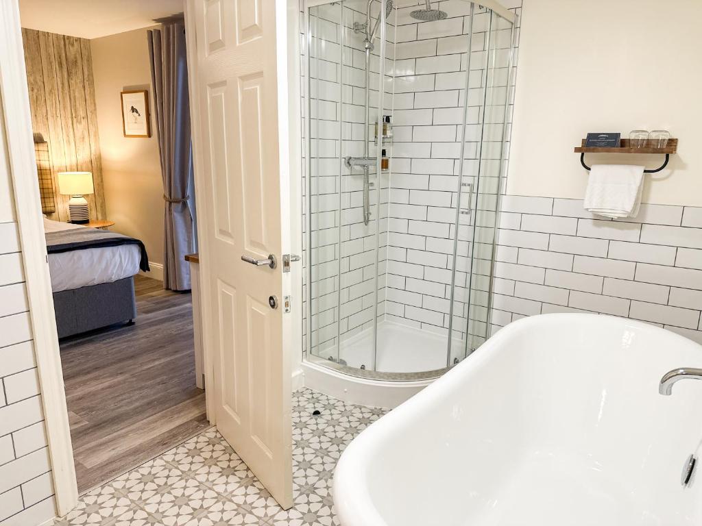 a bathroom with a bath tub and a shower at Beach House Hotel in Seahouses