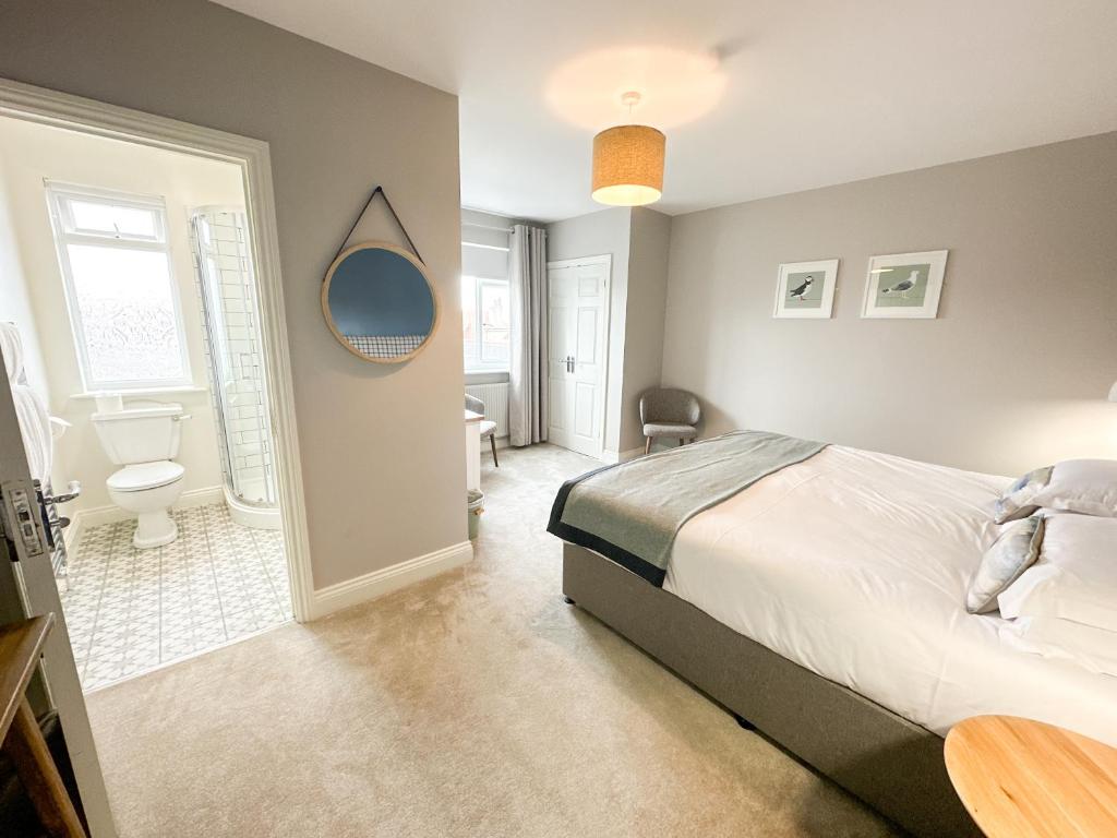 a bedroom with a bed and a bathroom with a toilet at Beach House Hotel in Seahouses
