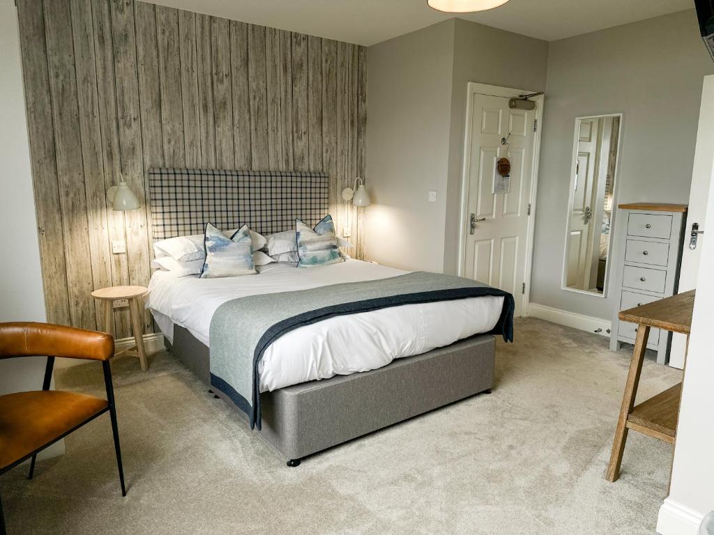 a bedroom with a large bed with blue pillows at Beach House Hotel in Seahouses