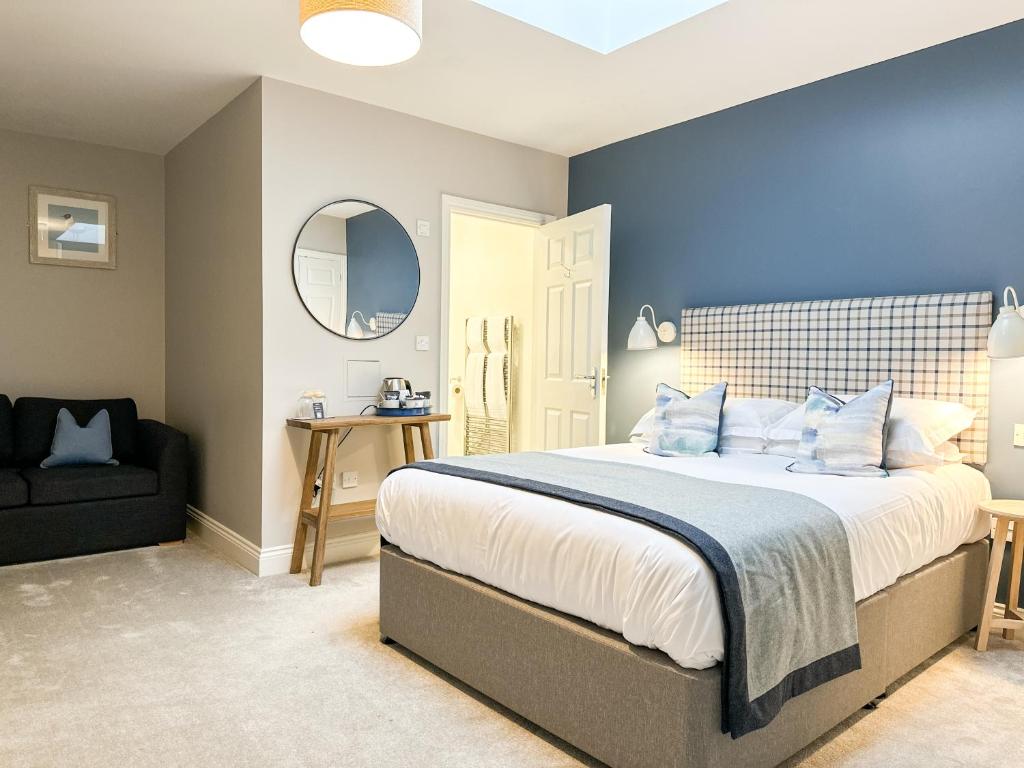 a bedroom with a large bed and a black chair at Beach House Hotel in Seahouses