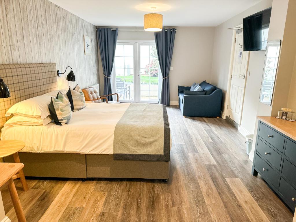 a bedroom with a large bed and a chair at Beach House Hotel in Seahouses