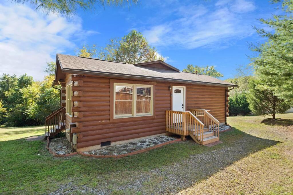 Cabaña de madera con porche y puerta blanca en Dream Weaver Cabin, en Candler