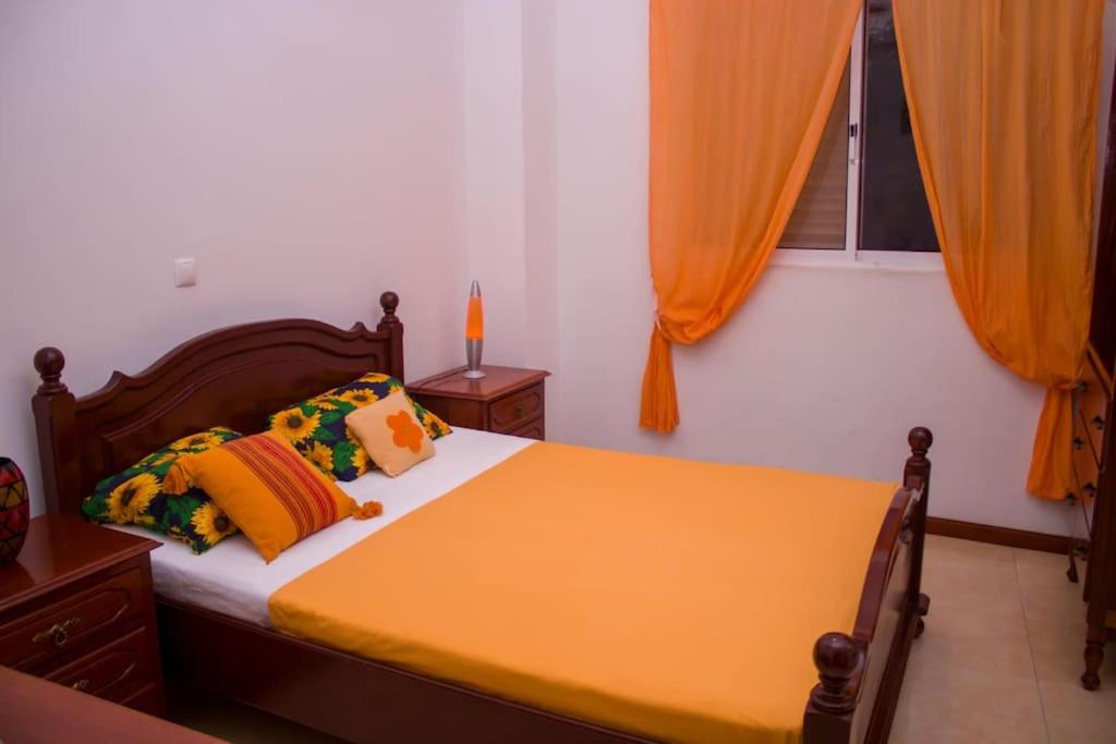 a bedroom with a bed with orange curtains at Casa Ramos Castro in Mindelo