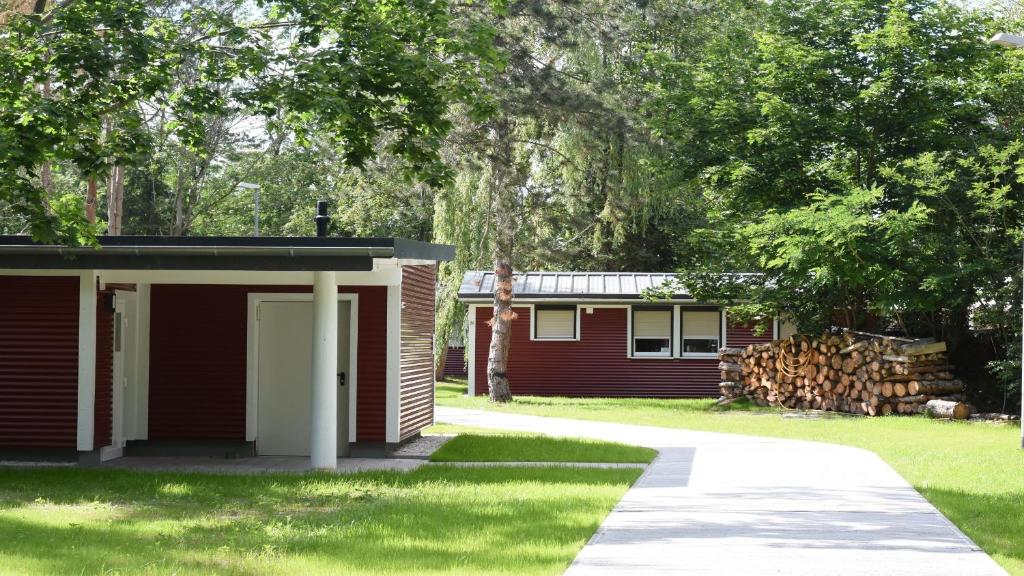a small red cabin with a yard with trees at Feriendorf am Flämingbad Bungalow in Coswig