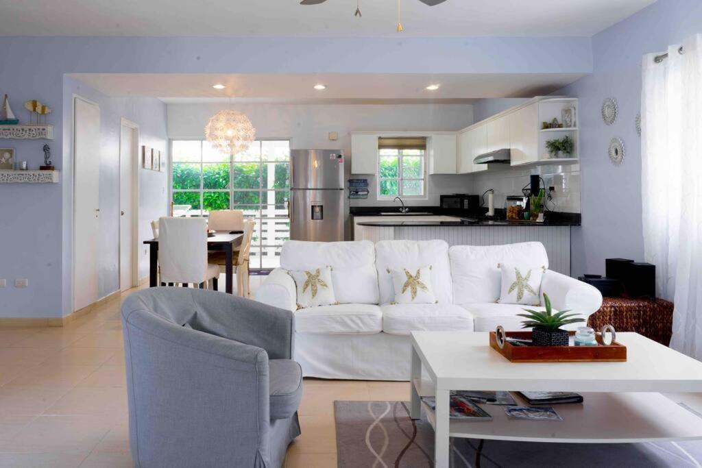 a living room with a white couch and a kitchen at VIlla Caracol in Punta Cana