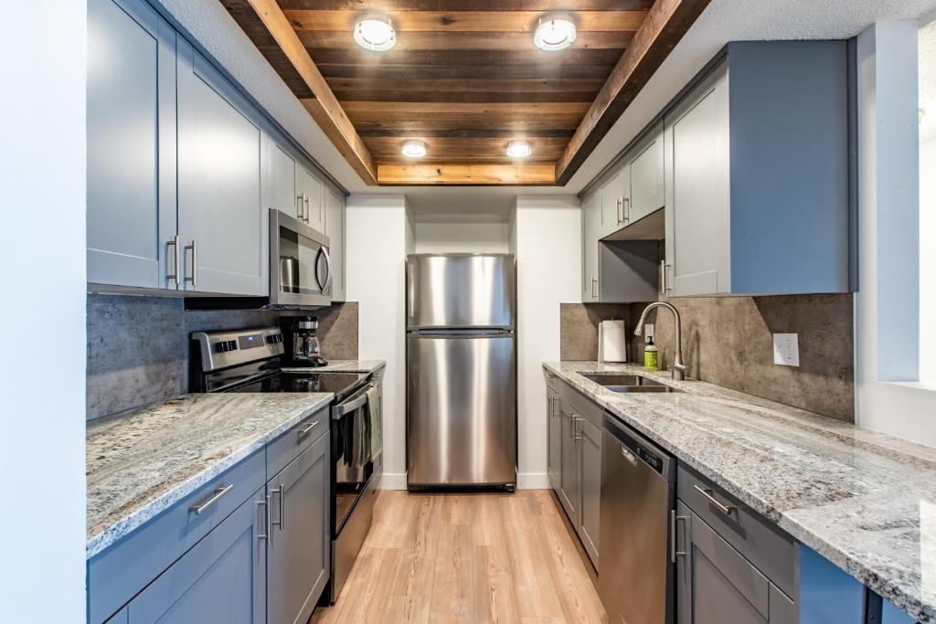 a kitchen with blue cabinets and a stainless steel refrigerator at Modern 2 Bed/1 Bath, In-Unit Laundry, Parking + 6 Blocks from Mayo in Rochester