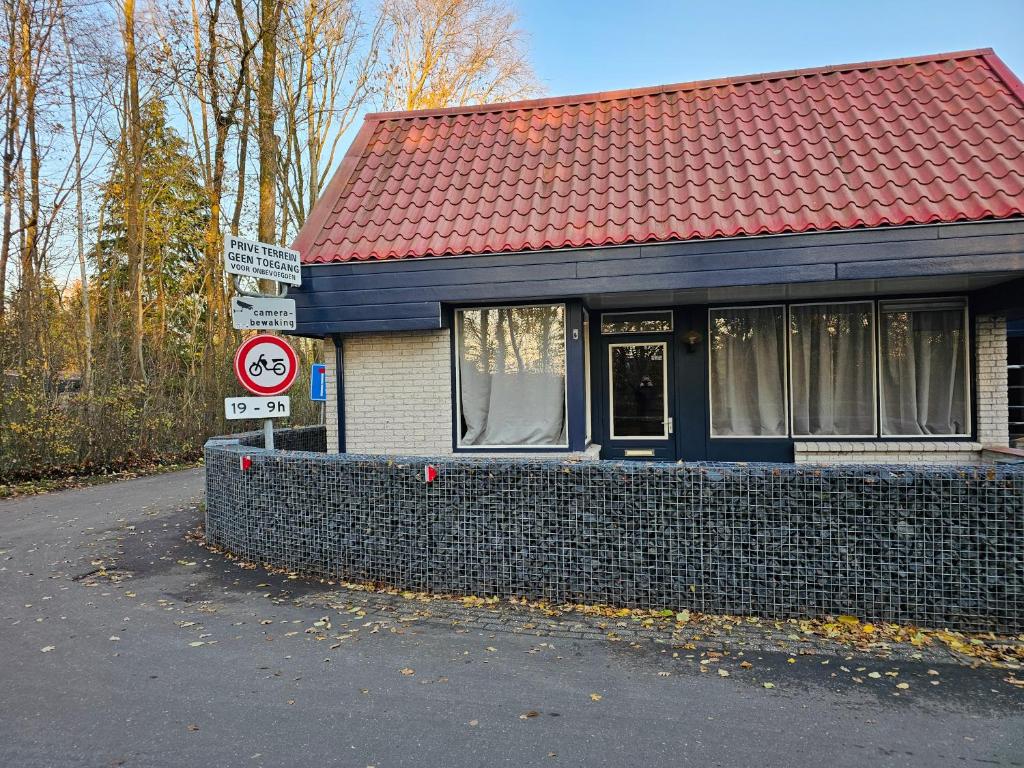 a building with a red roof and a brick wall at Vakantiehuis Zuiderveld in Geesbrug