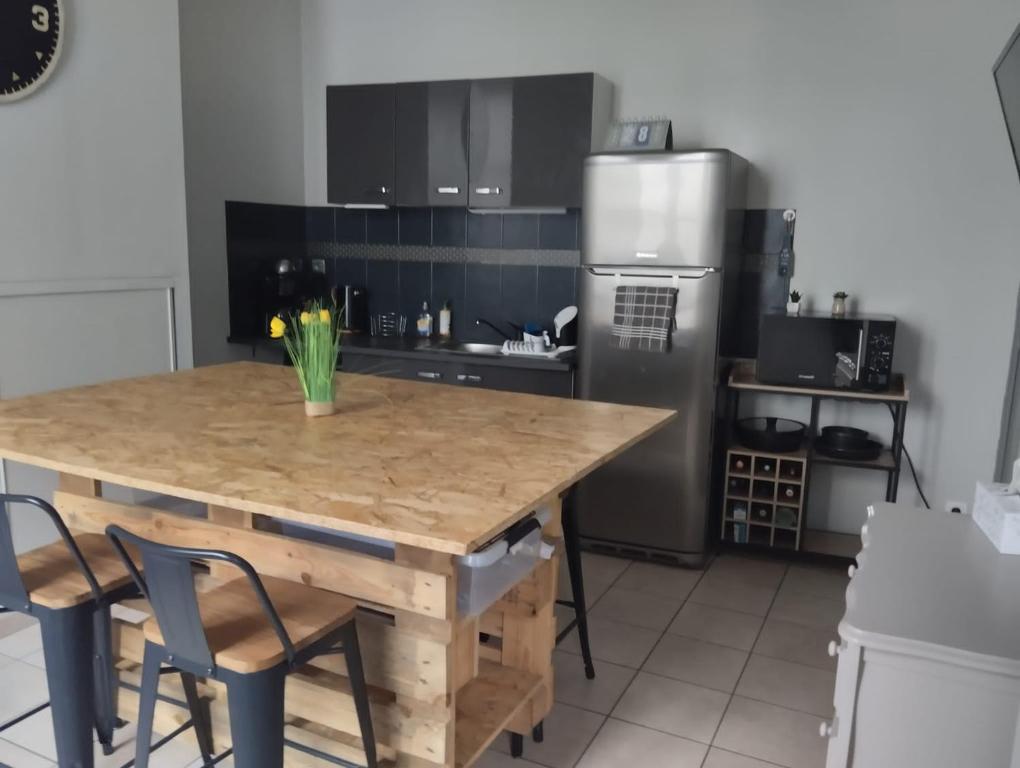 une cuisine avec une table en bois et un réfrigérateur dans l'établissement Petite maison de ville ernée centre, à Ernée