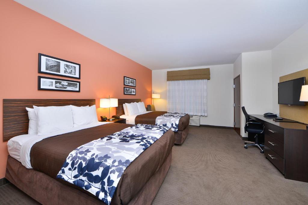 a hotel room with two beds and a desk at Sleep Inn & Suites Austin – Tech Center in Austin