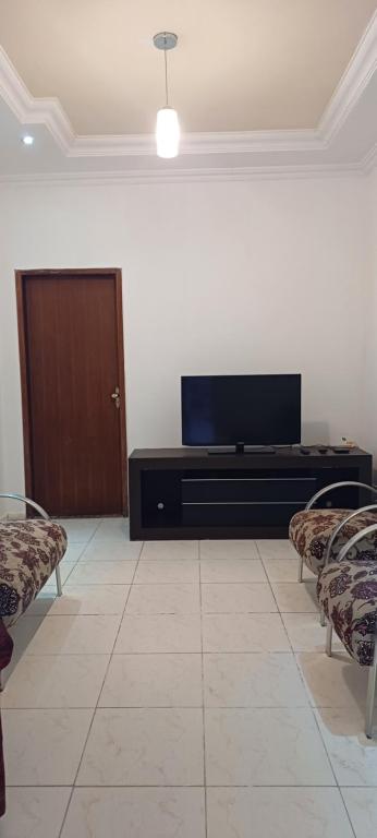 a living room with a flat screen tv and two chairs at LM Home 1 - casa com 2 quartos in Governador Valadares