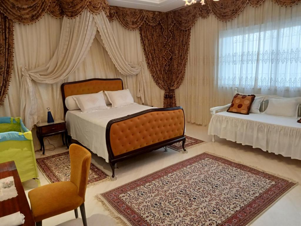 a bedroom with a bed and a couch and curtains at Chez Mme Jaouida in El Mourstane