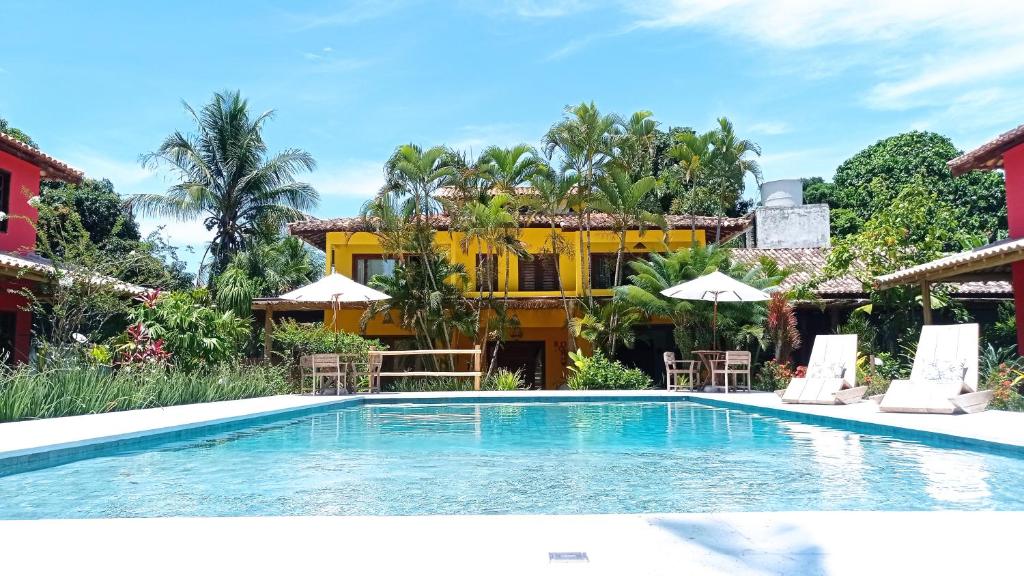 una piscina con sillas y sombrillas frente a un edificio en Machê Pousada & Boutique - A mais charmosa de Arraial D ajuda, en Arraial d'Ajuda