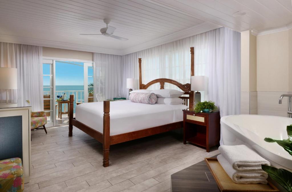 a bedroom with a bed and a tub and a television at Ocean Key Resort & Spa, a Noble House Resort in Key West