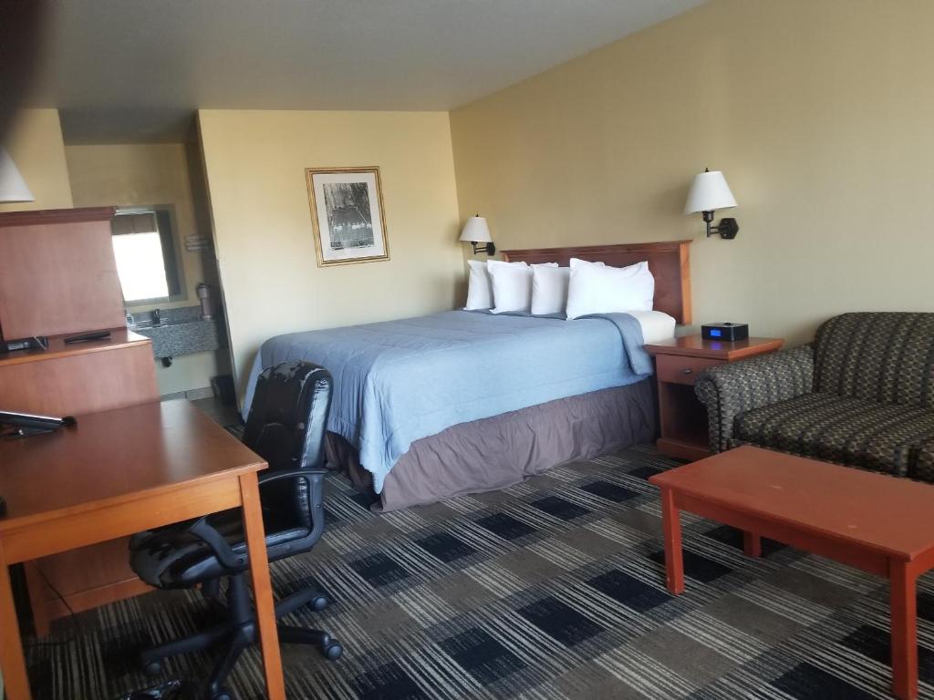 a hotel room with a bed and a desk and a chair at Oakridge Inn & Suites in Oakridge