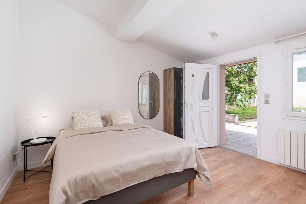 a white bedroom with a large bed and a doorway at Lumignons Lyonnais - Doua in Villeurbanne