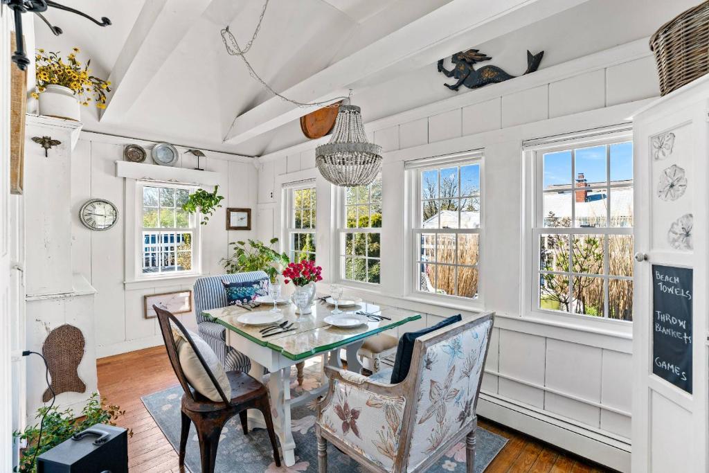 a dining room with a table and chairs and windows at Cottage Serenity Haven in Barnstable