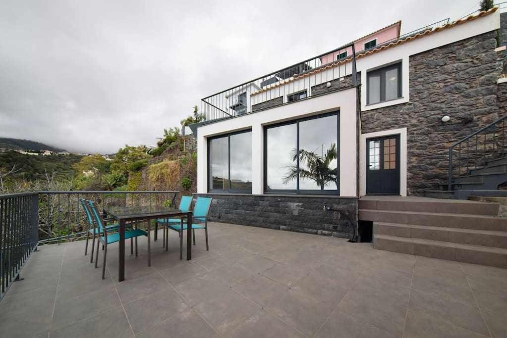 un patio con tavolo e sedie e un edificio di Lombo do Doutor Cottage 2 by Mth a Calheta