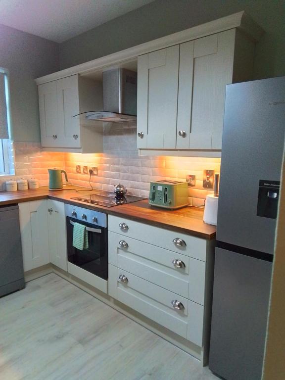 uma cozinha com armários brancos e um frigorífico branco em John & Mary's em Dromore