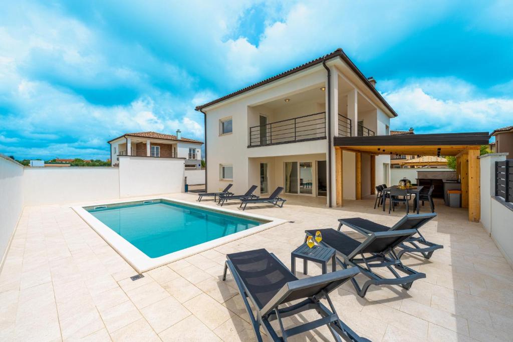a patio with a pool and chairs and a house at Villa D&J in Vodnjan
