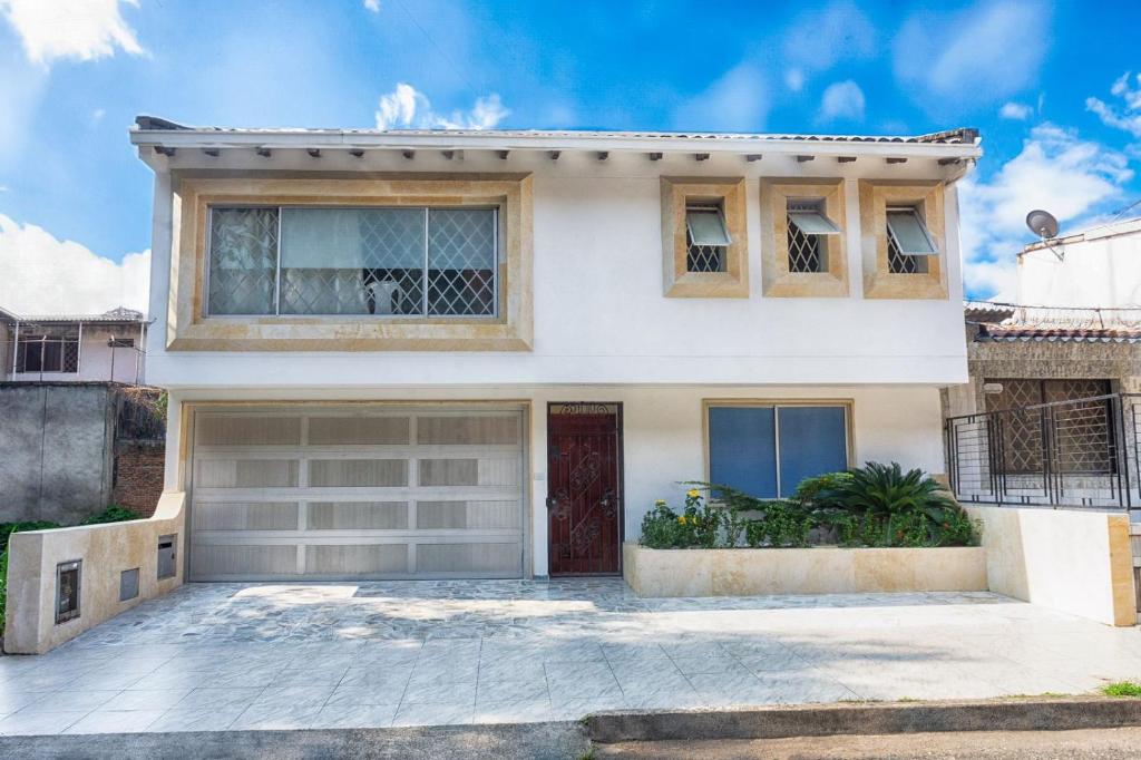 une maison blanche avec une porte rouge dans l'établissement Apartahotel Romor, à Cali