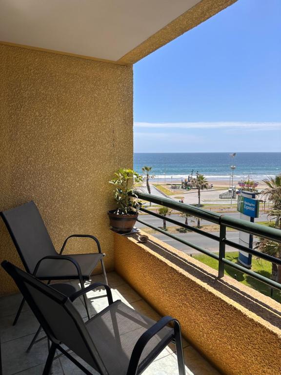 a balcony with two chairs and a view of the beach at Ideal familias, frente a la playa. Excelente ubicación in Iquique